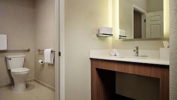 A bathroom with a toilet, a sink, a mirror, and a towel rack.