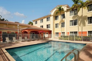A swimming pool with a metal ladder, surrounded by a white fence, with buildings in the background. - Residence Inn By Marriott Fort Lauderdale Weston (Weston)