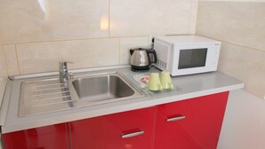 A kitchen with a stainless steel sink, a white microwave, and a kettle. - Concorde Hotel Ascot (Düsseldorf)