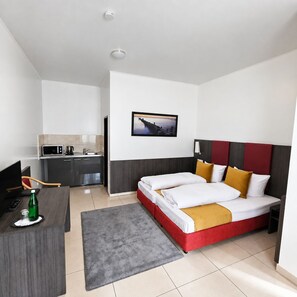 Een hotelkamer met een bed, bureau, magnetron, wastafel en een schilderij aan de muur.