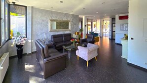 A modern hotel lobby with leather sofas, a glass coffee table, and a large mirror on the wall. - Concorde Hotel Ascot (Düsseldorf)