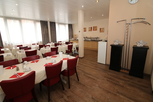 Comedor de hotel con varias mesas dispuestas para comer, una cocina al fondo y una recepción.