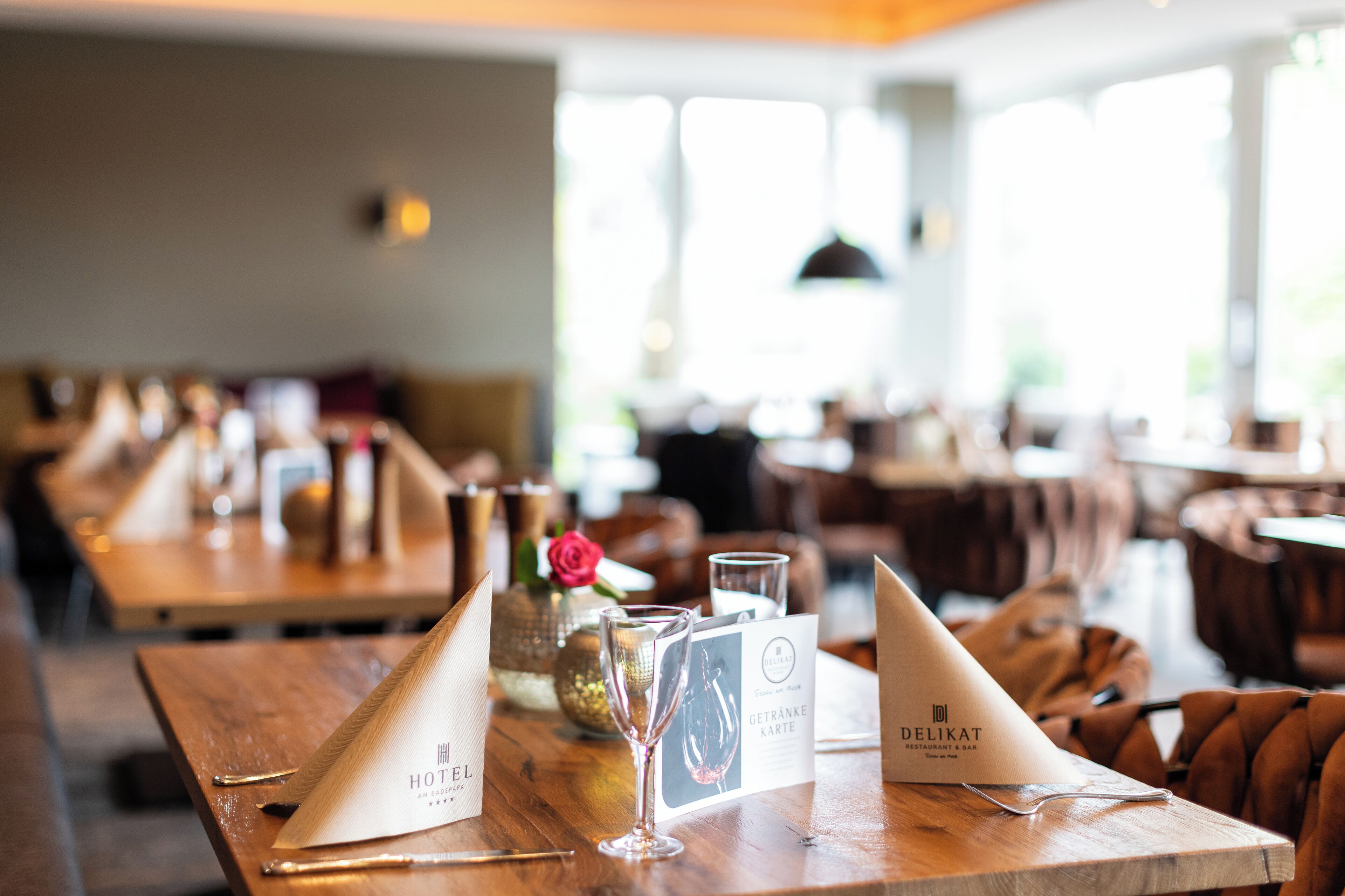 Un'ambientazione da ristorante con tavoli in legno, menu e un bicchiere di champagne.