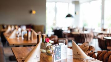 Un'ambientazione da ristorante con tavoli in legno, menu e un bicchiere di champagne.