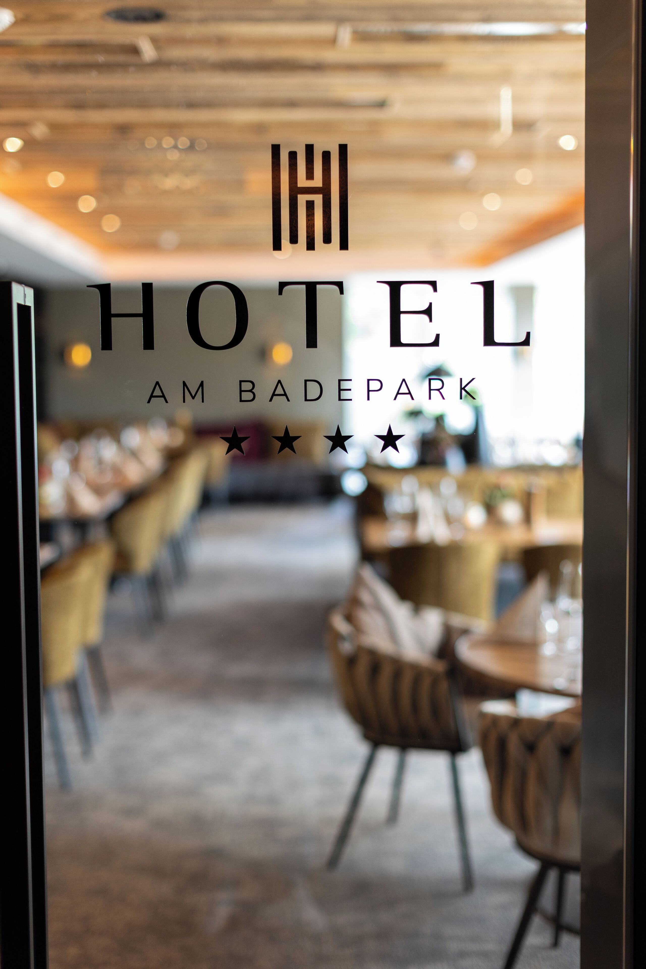 A hotel interior with a modern design, featuring a long dining area with tables and chairs.