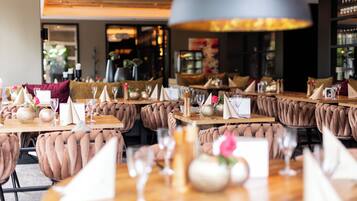 Um restaurante com mesas de madeira, cadeiras estofadas e um grande lustre.