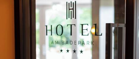 A hotel sign with the name "HOTEL AM BADERPARK" and a star rating of three stars.