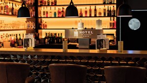Zona de bar con minibar, botellas e iluminación colgante.
