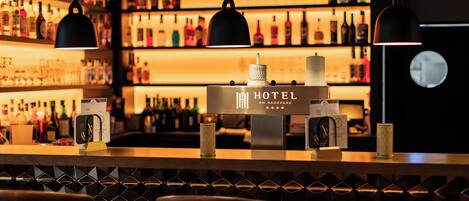 Zona de bar con minibar, botellas e iluminación colgante.