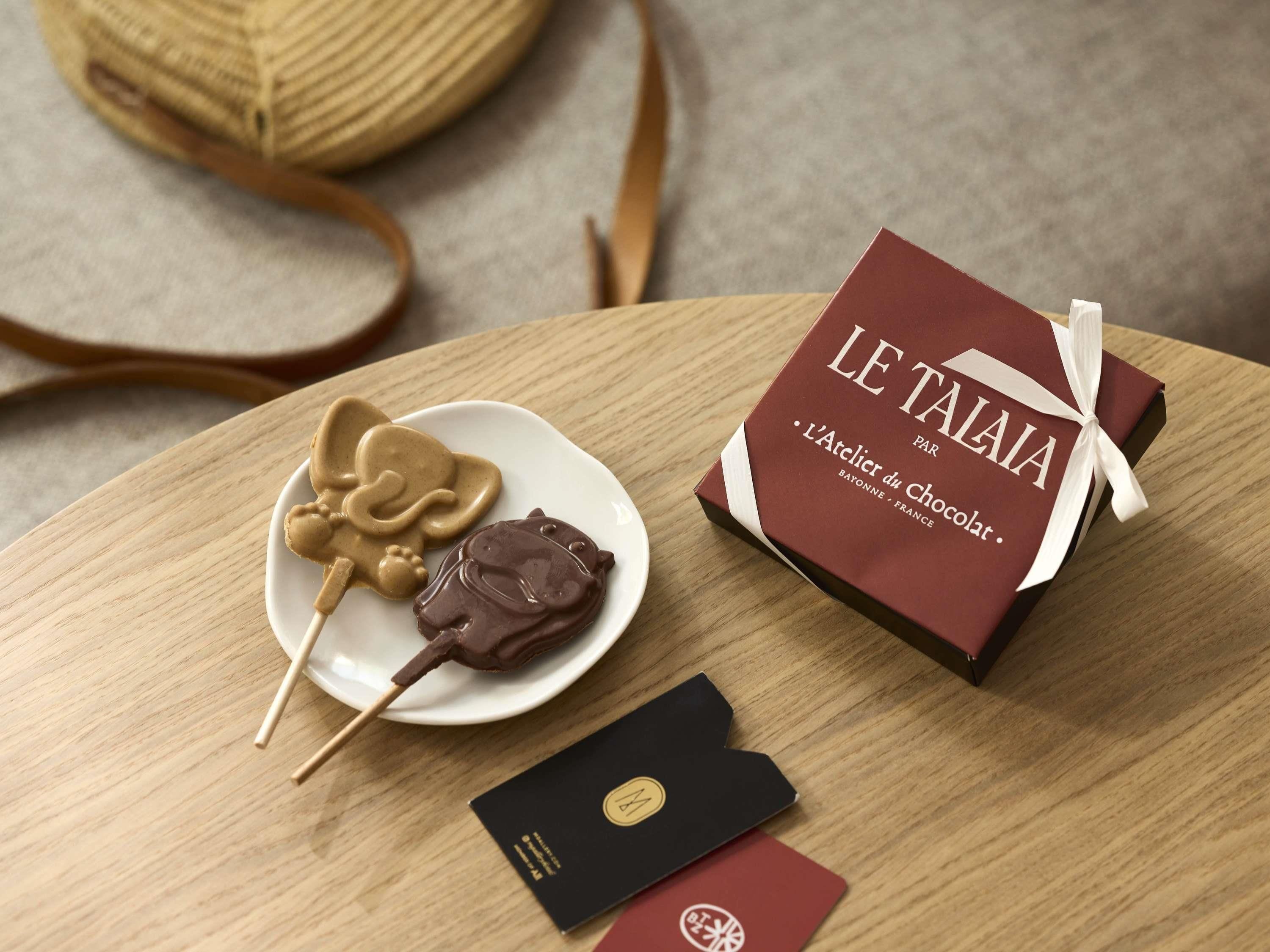 Una mesa de madera con un dulce cubierto de chocolate, una caja de regalo y una tarjeta.