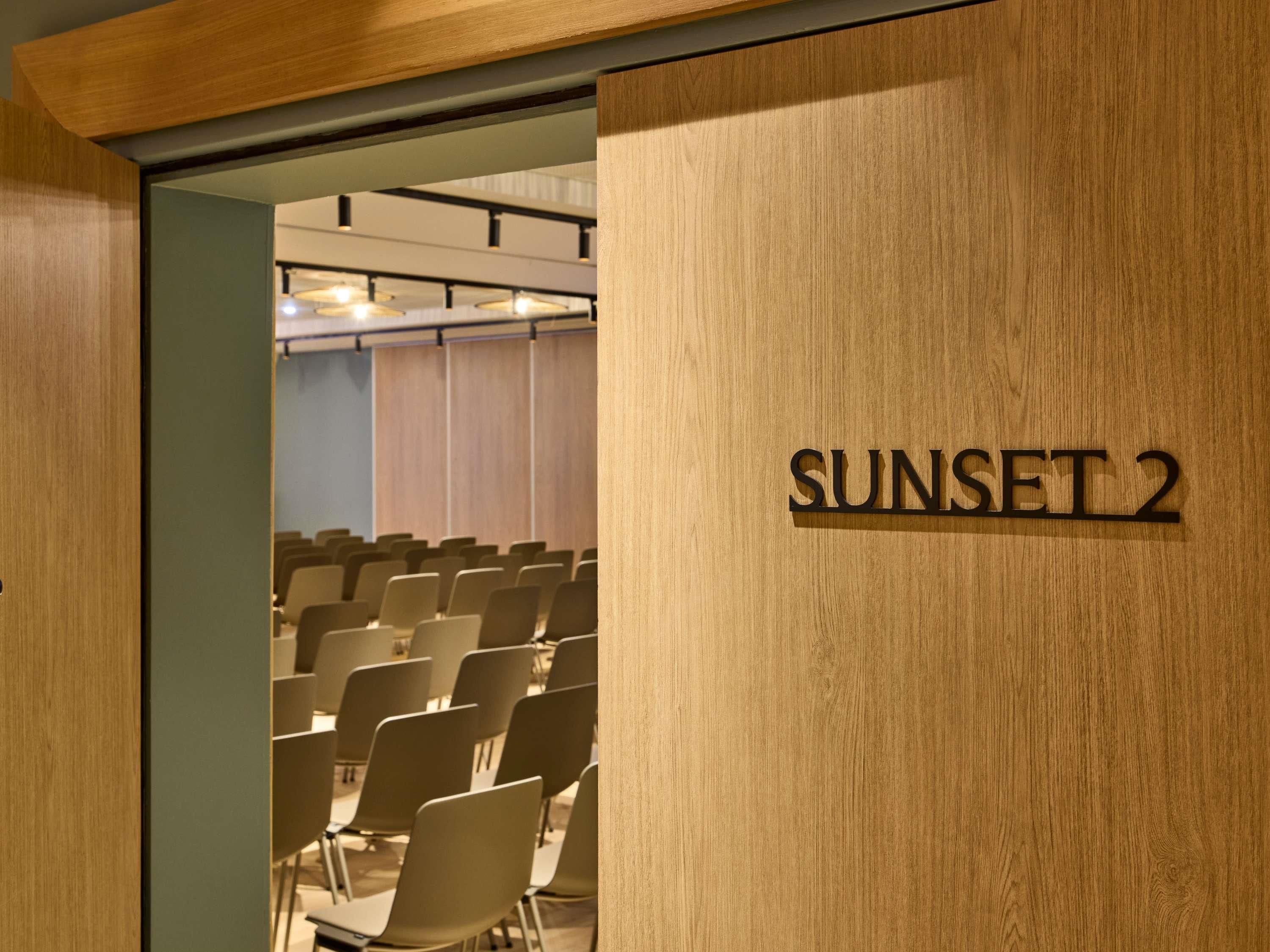 Un salón de conferencias con filas de sillas y un cartel que dice 'SUNSET 2'.