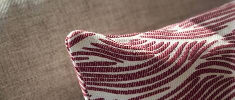 A close-up of a fabric with a red and white pattern on a beige couch.