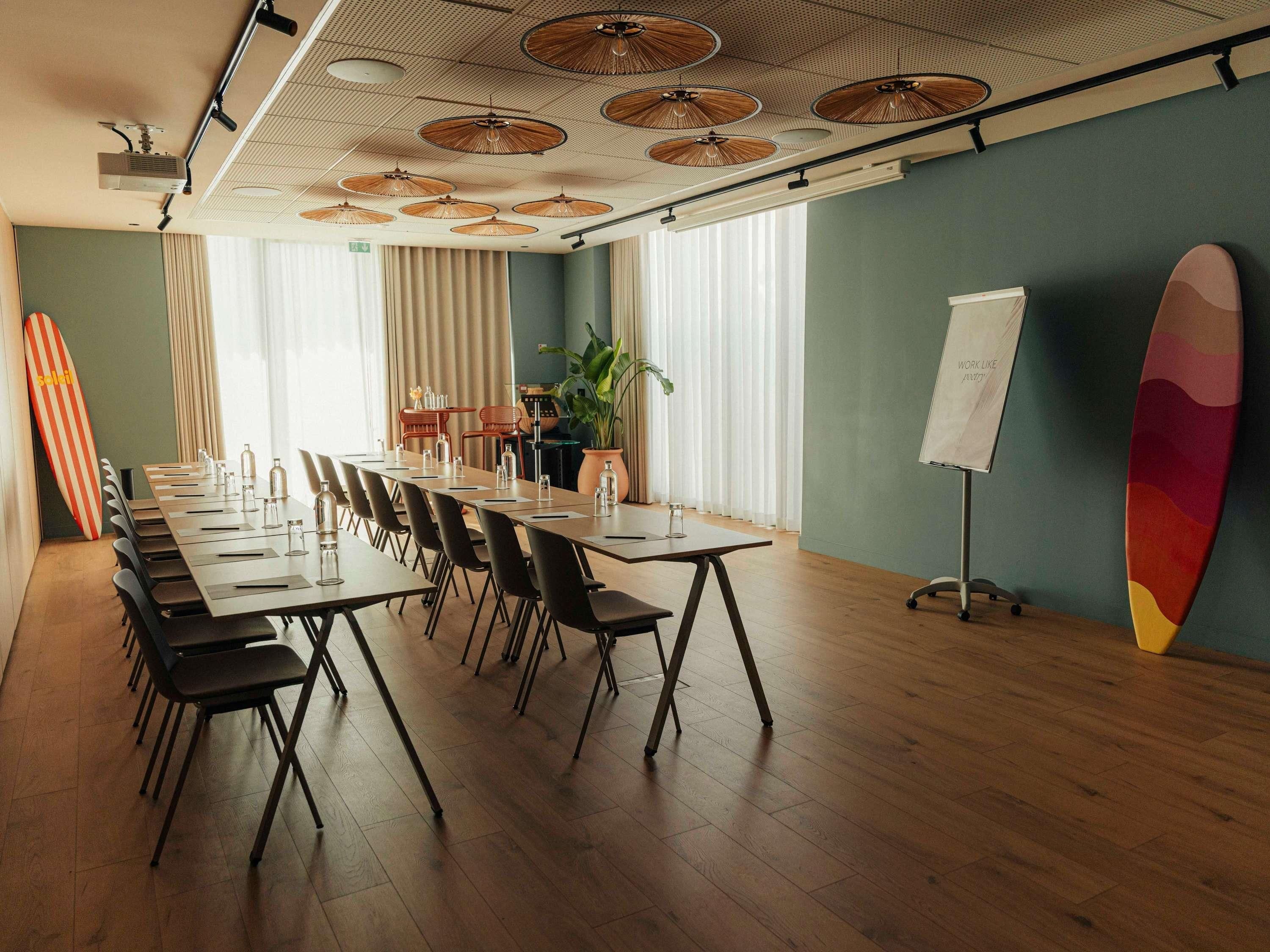 A conference room with a long table, chairs, a whiteboard, and surfboards.
