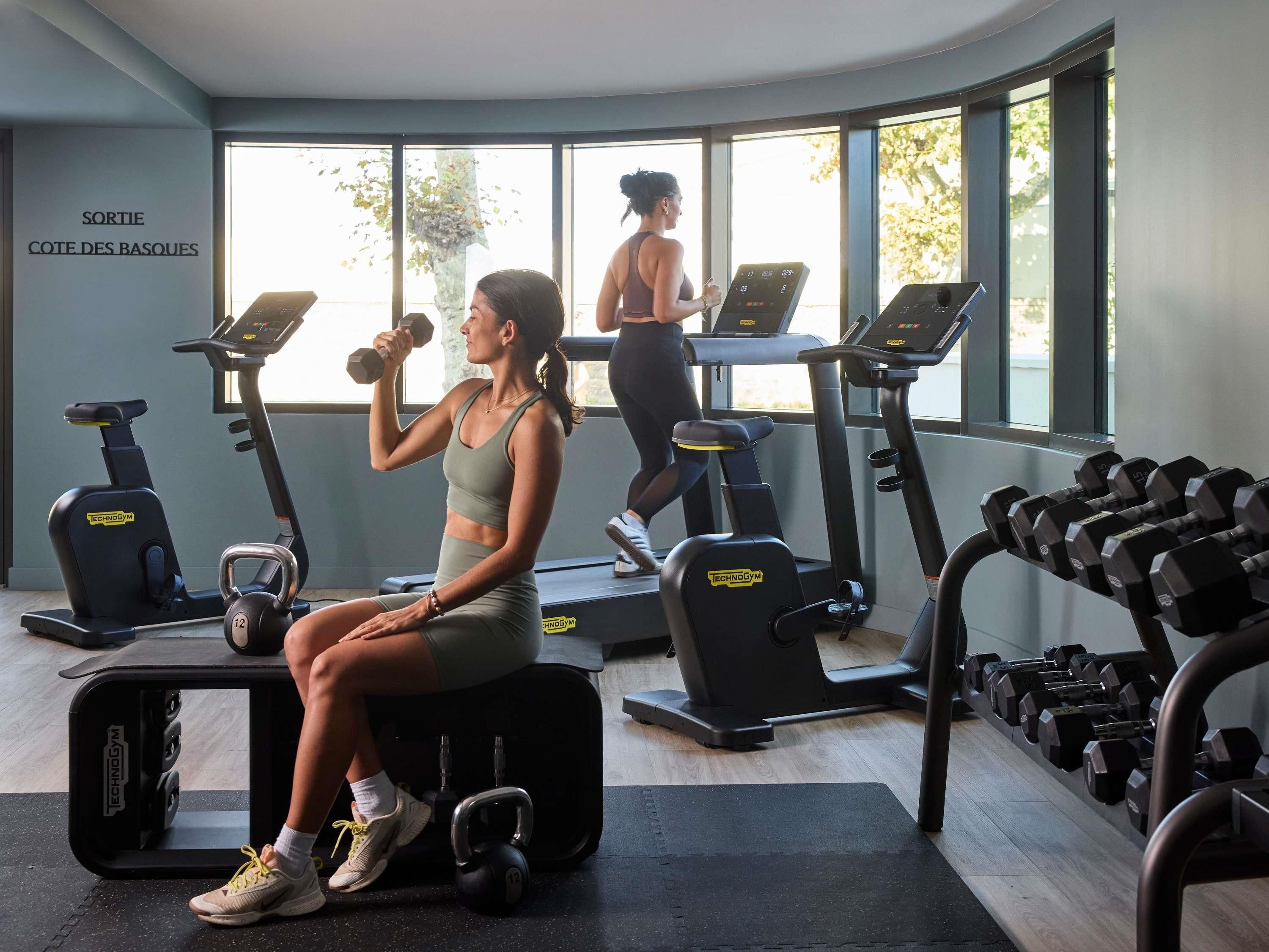 Une salle de sport équipée de tapis de course, d’haltères et de kettlebells.
