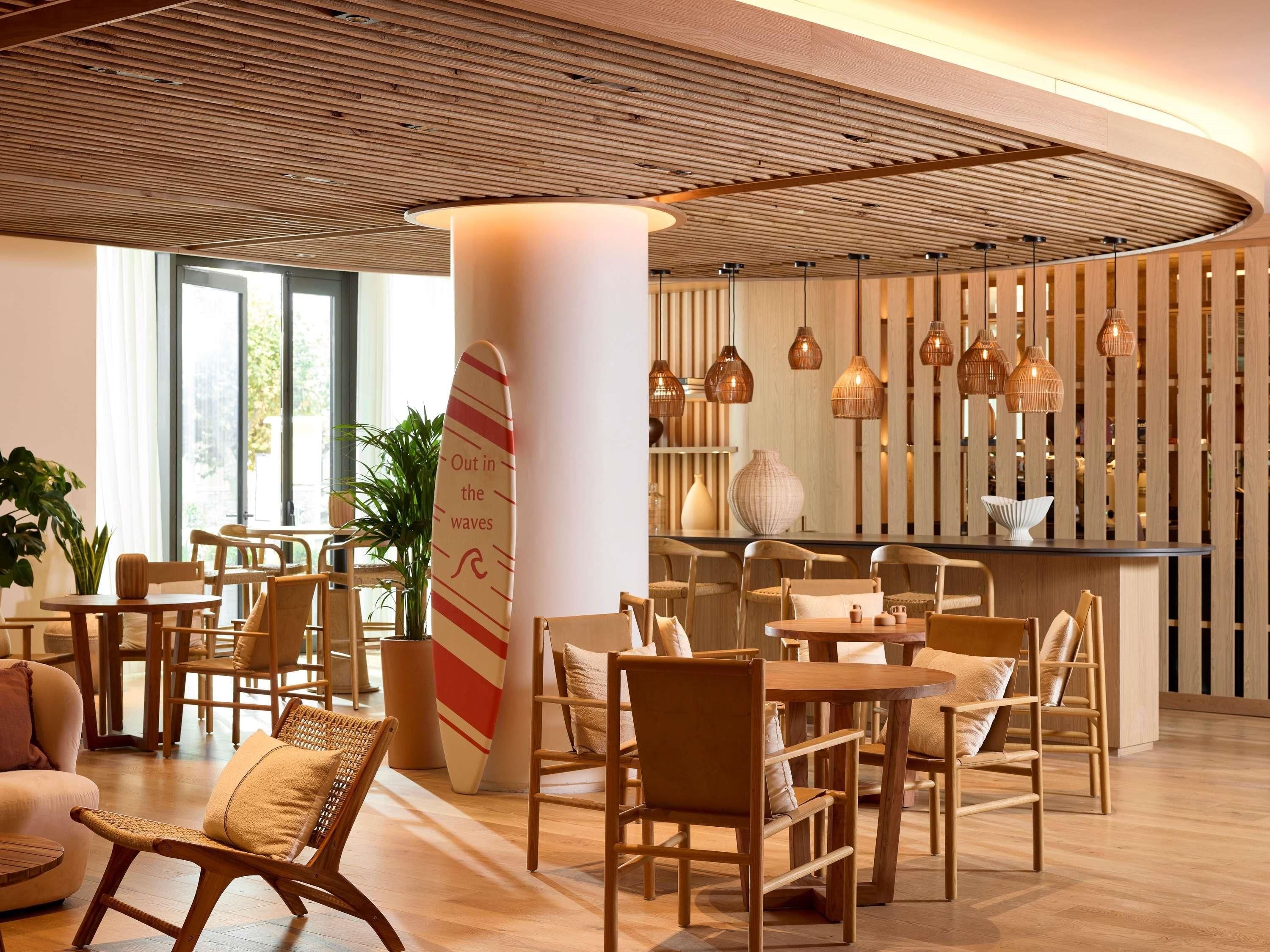 A modern interior with wooden furniture, a surfboard, and a wooden ceiling.