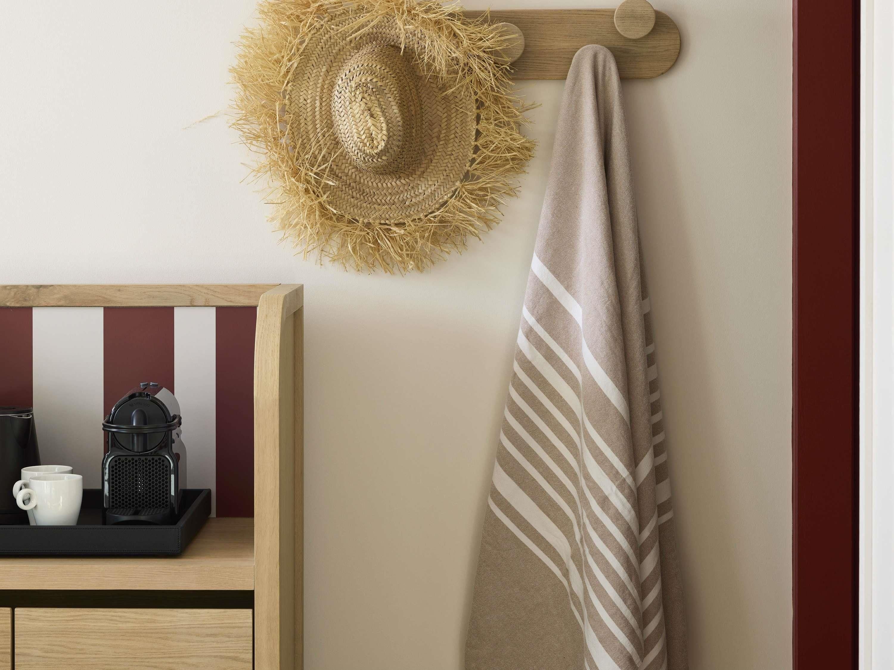 A kitchen area with a coffee maker, a tray with two white mugs, and a hanging straw hat.