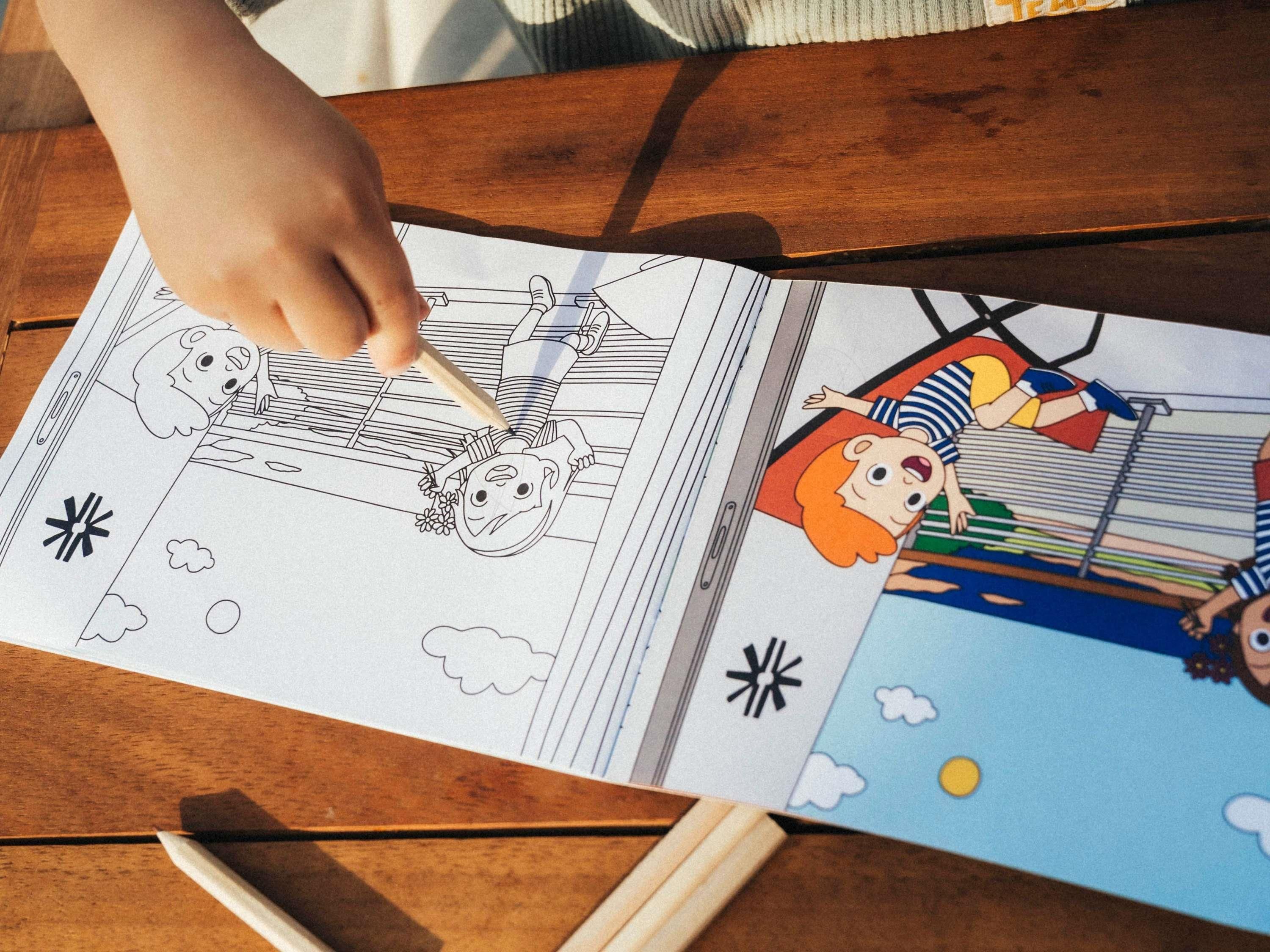 Uma pessoa colorindo um livro com personagens de desenho animado.