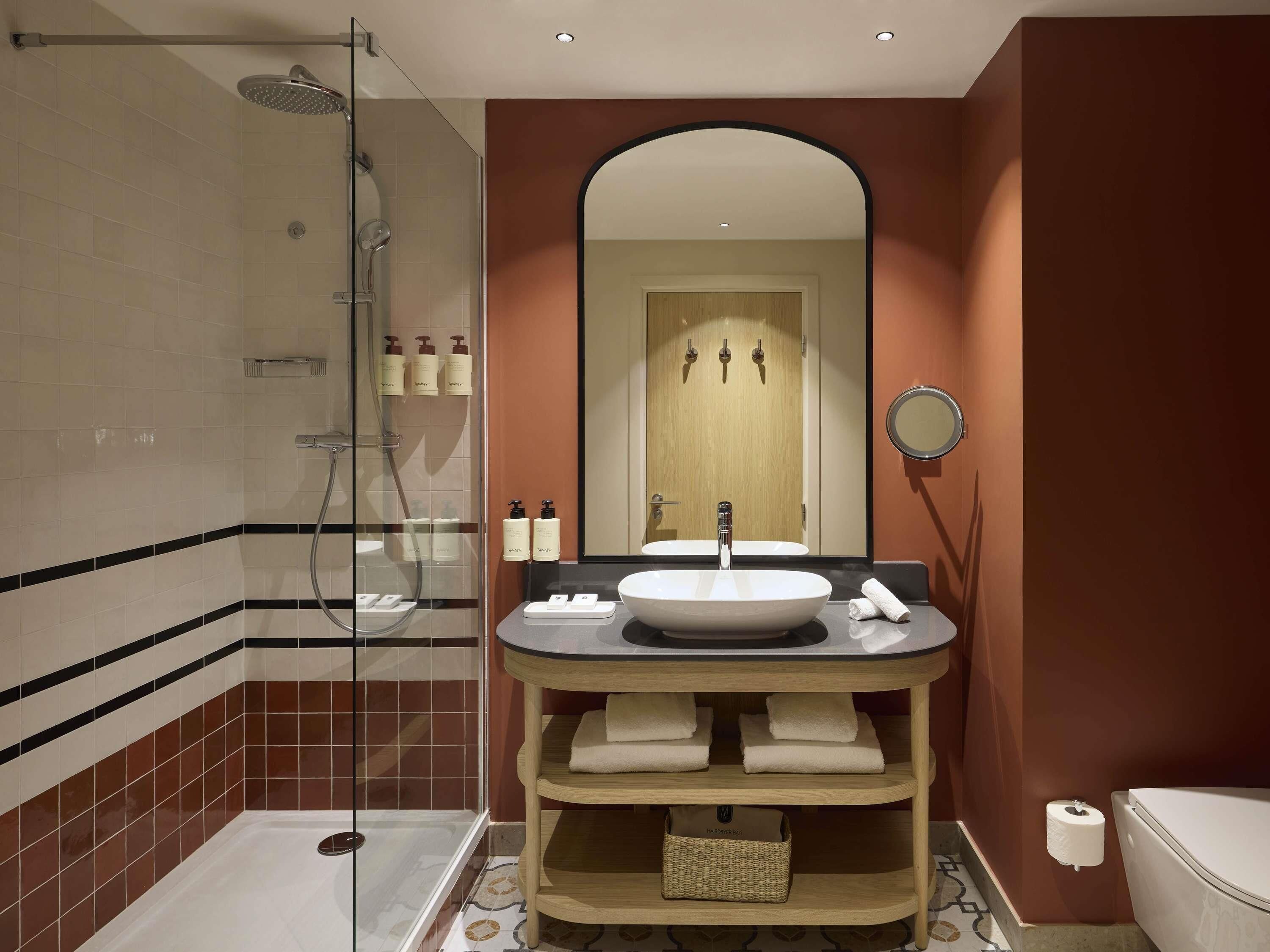 Une salle de bain avec une douche à parois de verre, un lavabo avec un miroir et des toilettes.