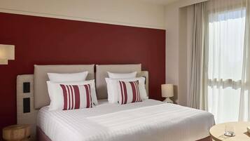 A hotel room with a large bed, two bedside tables, a round table, and a ceiling fan.