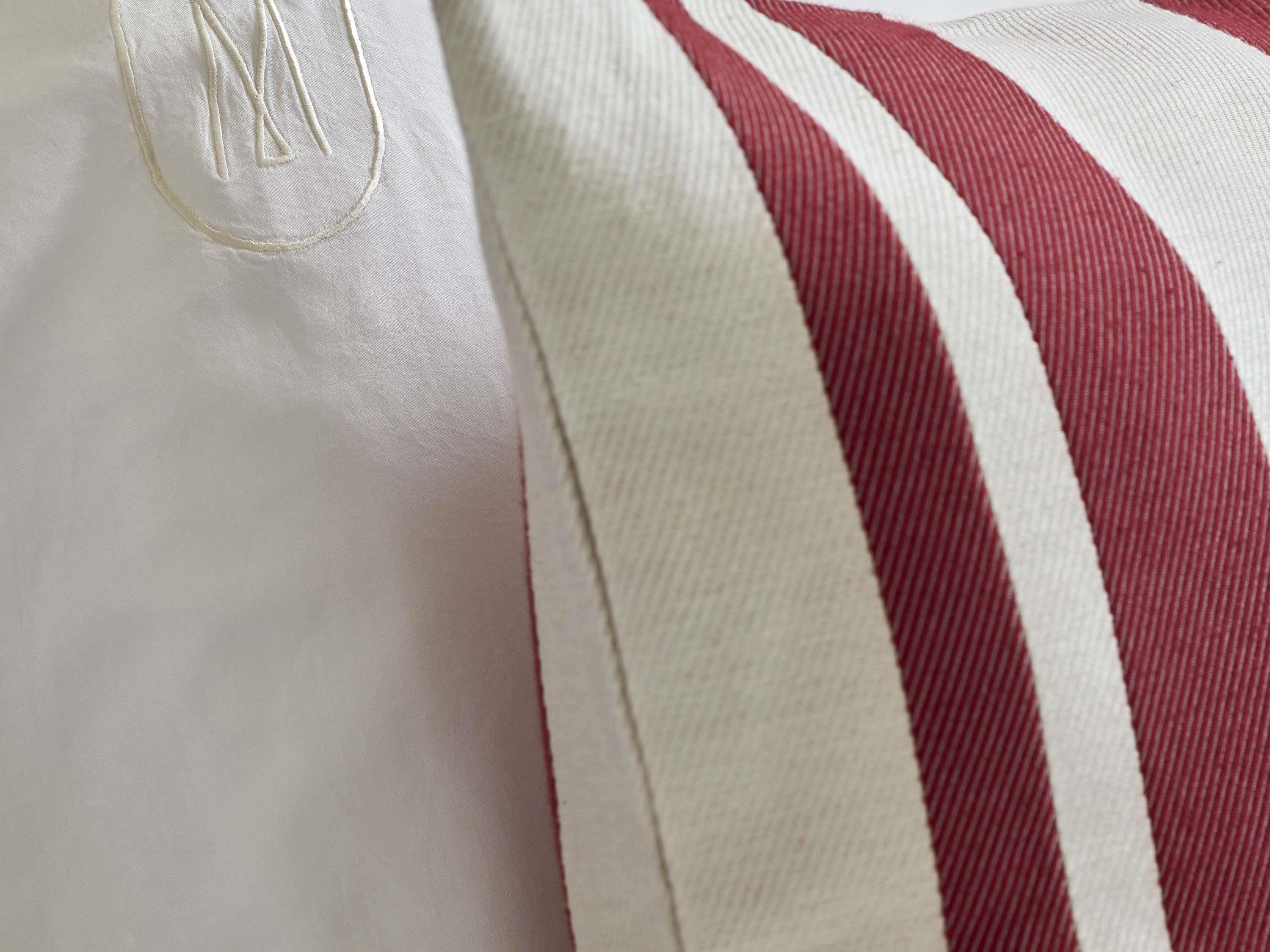 A close-up of a white fabric with a red and white striped pattern and a monogram.