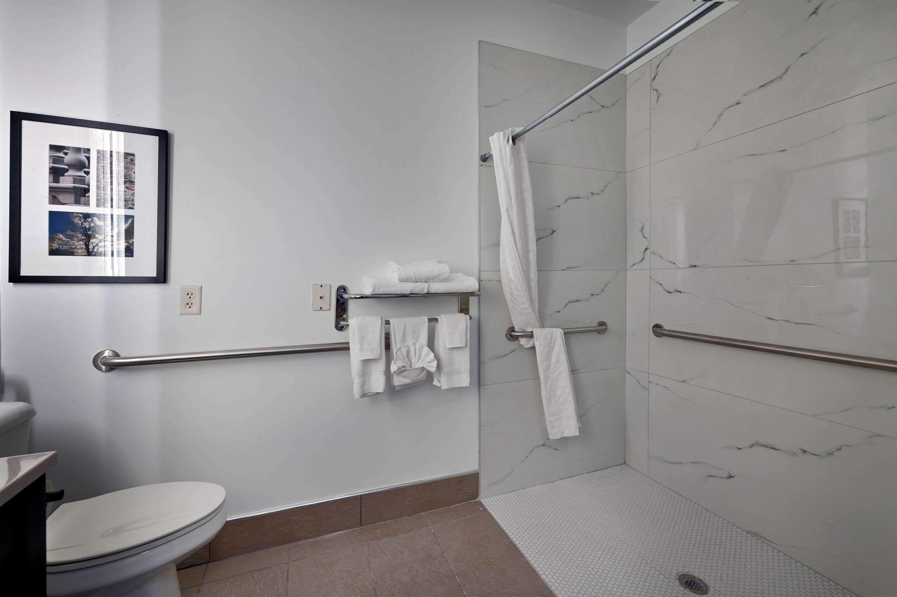 A modern bathroom with a toilet, a shower with a glass door, and a towel rack with folded towels.