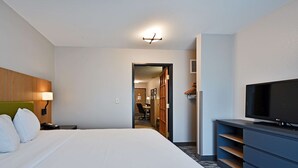 A hotel room with a large bed, a TV, a desk, and a wardrobe.