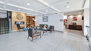 A modern living room with a sofa, two armchairs, a coffee table, and a wooden bookshelf.