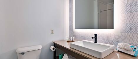 A bathroom with a white sink, a mirror, and a toilet.