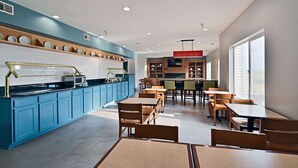 A modern restaurant with blue cabinets, wooden tables, and a central counter. - Country Inn & Suites by Radisson, Bloomington-Normal Airport, IL (Bloomington)