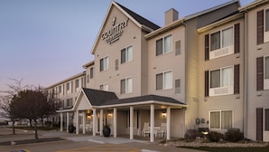 A hotel with a covered front porch, multiple windows, and a sign indicating it is a Country Inn & Suites.