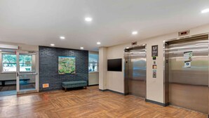 A modern lobby with wooden flooring, a bench, a digital clock, and two elevators. - Extended Stay America Premier Suites Miami Coral Gables (Miami)