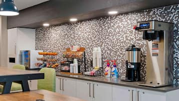 A modern kitchen with a coffee station, a refrigerator, and a microwave.