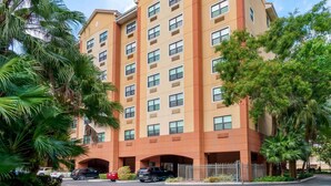 A multi-story hotel with a beige facade, multiple windows, and a parking area with several cars. - Extended Stay America Premier Suites Miami Coral Gables (Miami)
