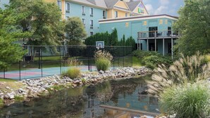 A hotel with a tennis court, a pond, and a building with a green facade. - Holiday Inn Express Holland by IHG (Holland)