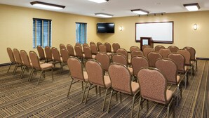 A conference room with rows of chairs, a projector screen, and a television. - Holiday Inn Express Holland by IHG (Holland)