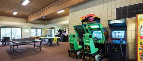 An indoor recreational area with arcade games, a ping pong table, and a large window.