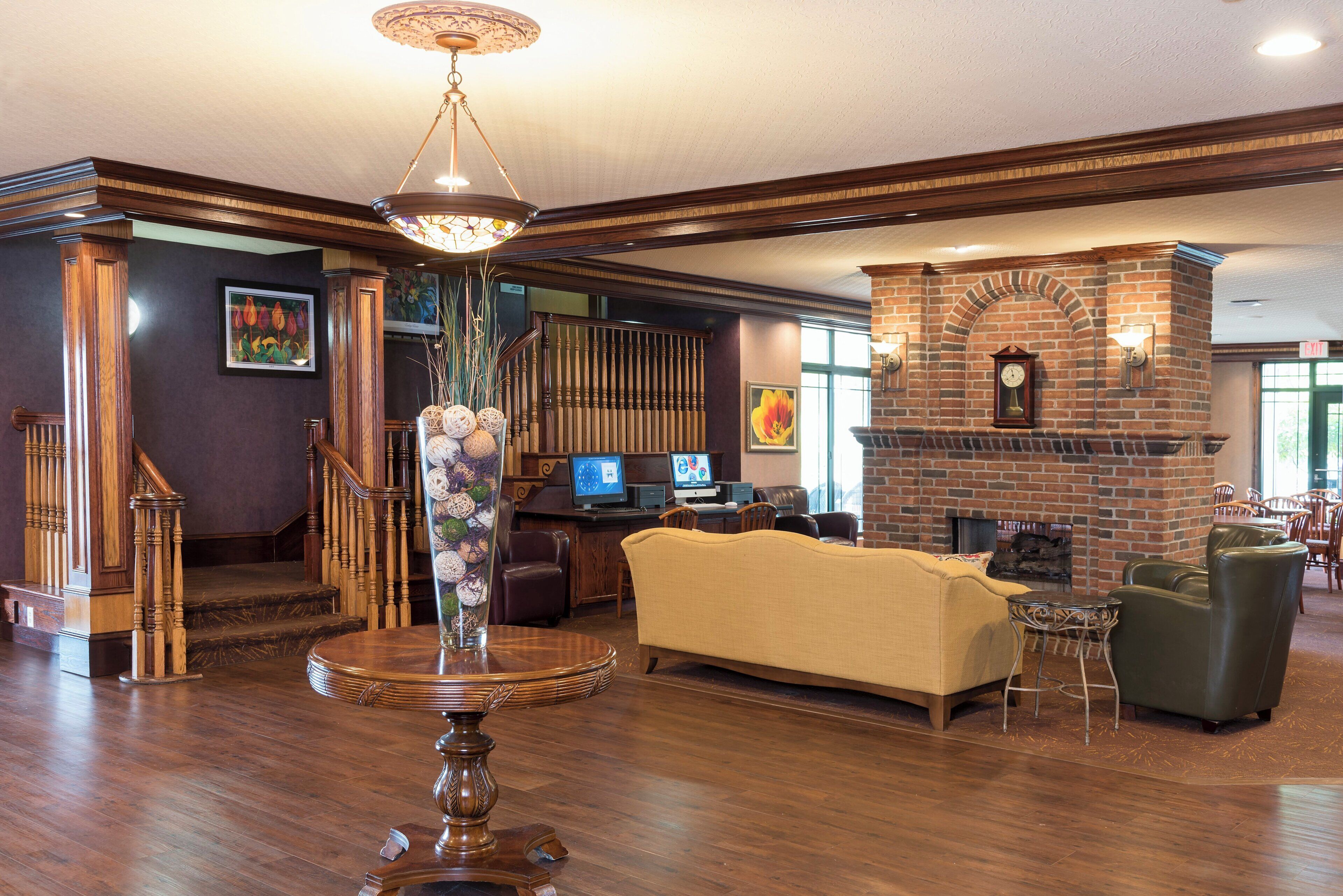 Un hall con escalera de madera, chimenea, mostrador de recepción y zona de estar.