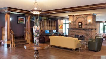 Un hall con escalera de madera, chimenea, mostrador de recepción y zona de estar.