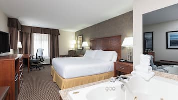A hotel room with a large bed, a desk with a chair, a television, a bathroom with a bathtub and sink, and a mirror.