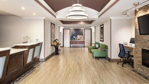 A reception area with a counter, seating, and a fireplace. - Holiday Inn Express & Suites Live Oak by IHG (Live Oak)