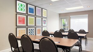 A conference room with a long table, multiple chairs, and framed artwork on the wall. - Holiday Inn Express & Suites Live Oak by IHG (Live Oak)
