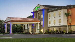 A hotel with a covered entrance, a sign indicating it is a Holiday Inn Express, and a well-maintained lawn area. - Holiday Inn Express & Suites Live Oak by IHG (Live Oak)