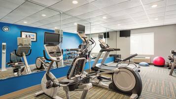 A gym with exercise equipment, a mirrored wall, and a blue accent wall.