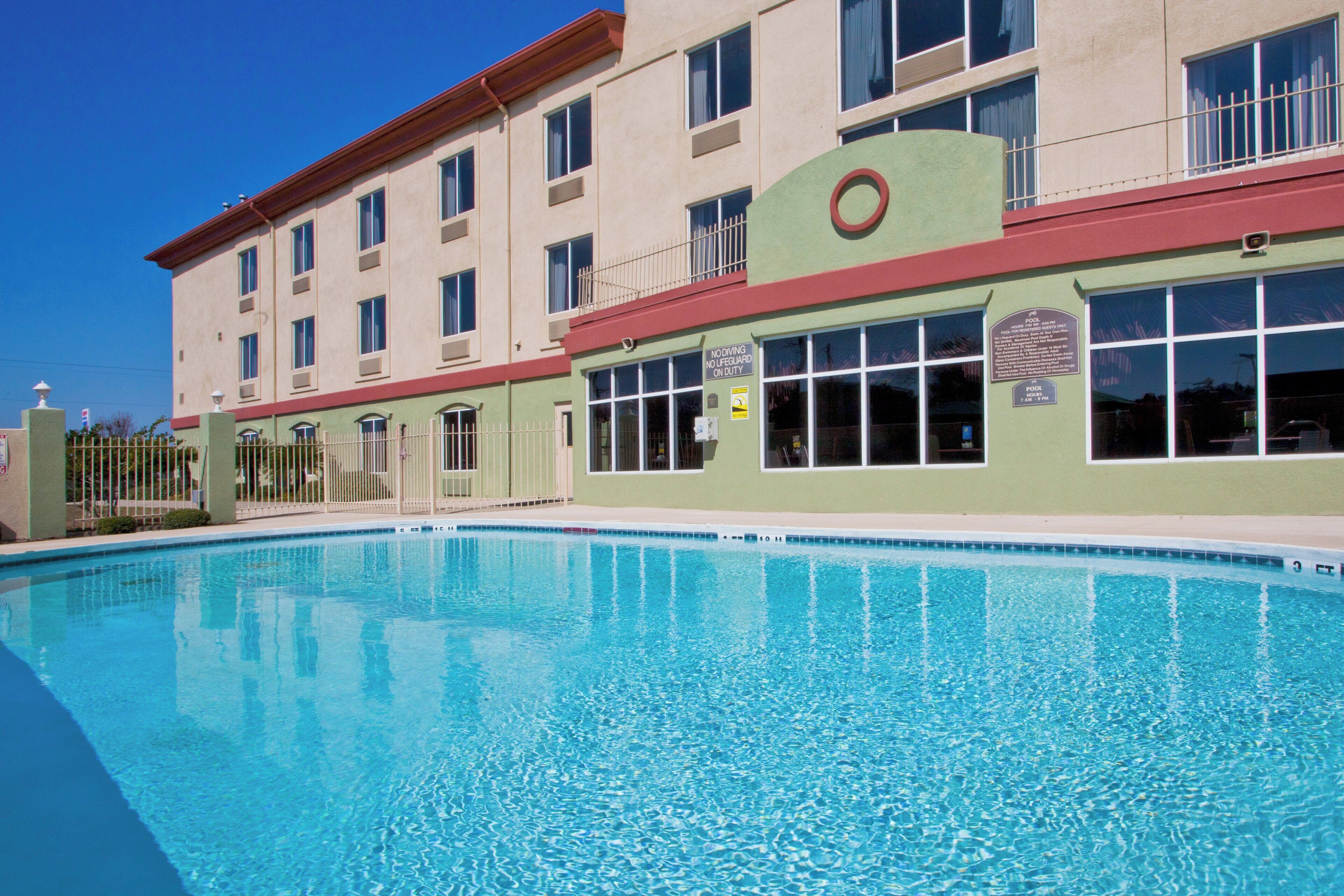 Hotel med swimmingpool, flere vinduer og et skilt, der angiver, at dykning ikke er tilladt, og der ikke er livredder på vagt.