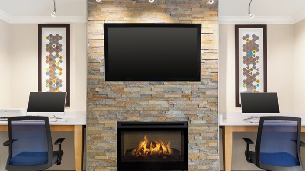 A conference room with a stone fireplace, a flat-screen TV, and two office chairs. - Holiday Inn Express & Suites Live Oak by IHG (Live Oak)