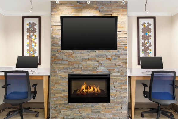 A conference room with a stone fireplace, a flat-screen TV, and two office chairs.