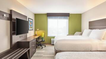 A hotel room with a bed, a desk with a chair, a television, and a window with blinds.