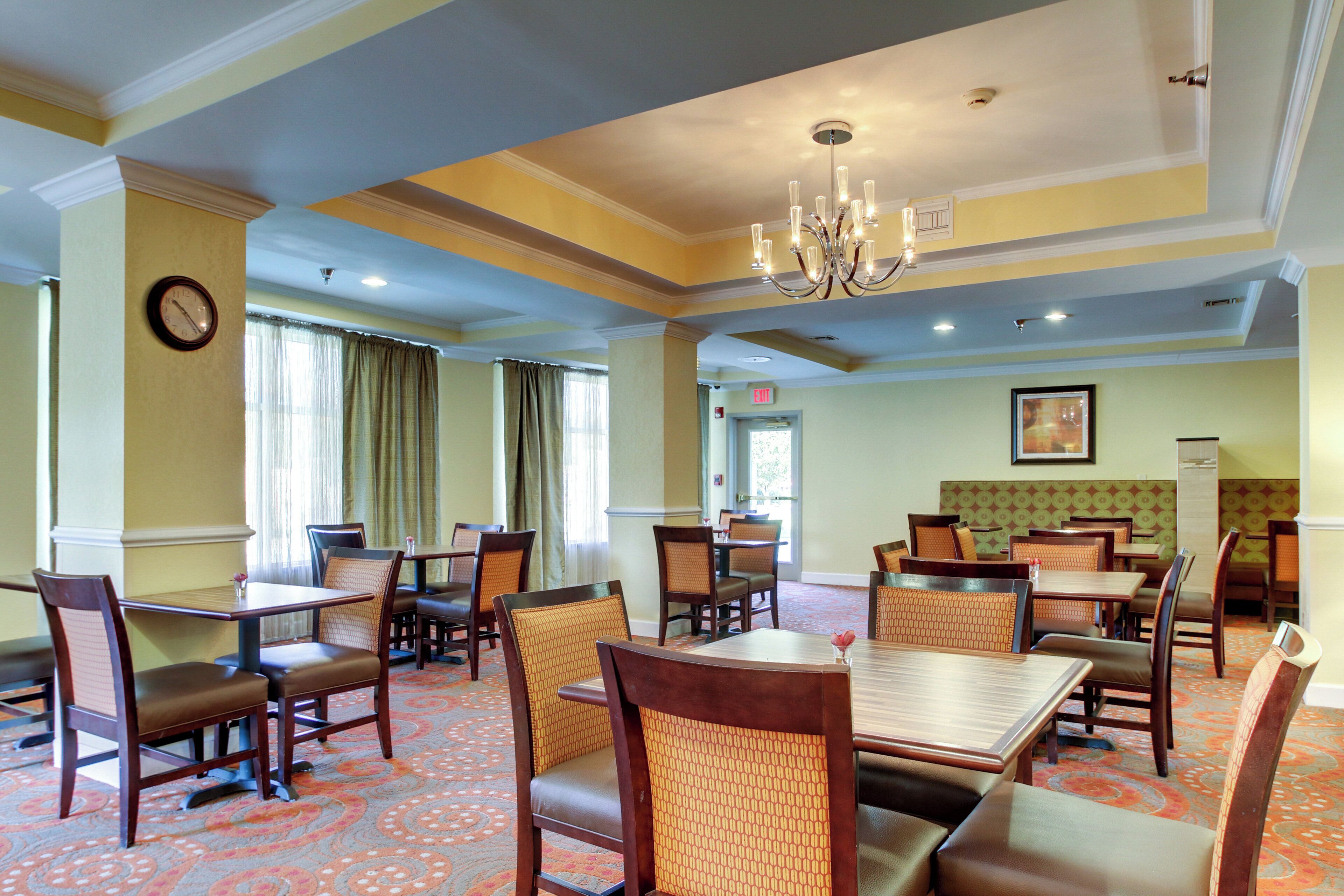 Un comedor de hotel con varias mesas y sillas, un candelabro y un reloj en la pared.