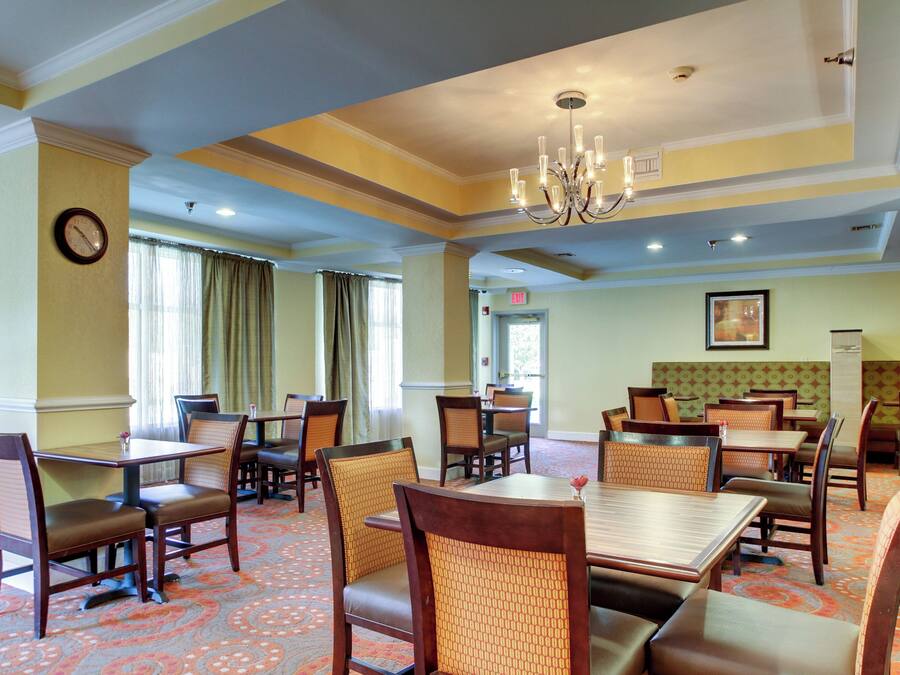 Un comedor de hotel con varias mesas y sillas, un candelabro y un reloj en la pared.