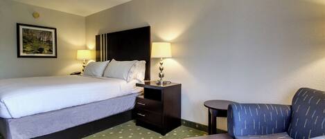 A hotel room with a bed, a desk, a chair, and a small table.